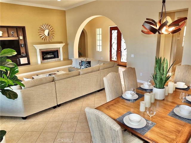 dining space featuring french doors, crown molding, light tile patterned floors, and a fireplace