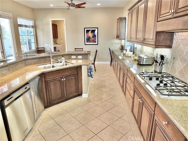 kitchen with sink, stainless steel appliances, light stone countertops, and light tile patterned floors