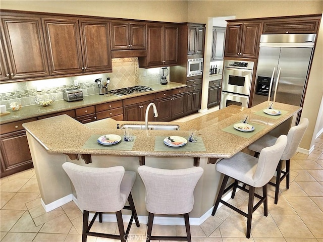 kitchen featuring sink, a breakfast bar area, built in appliances, and a spacious island