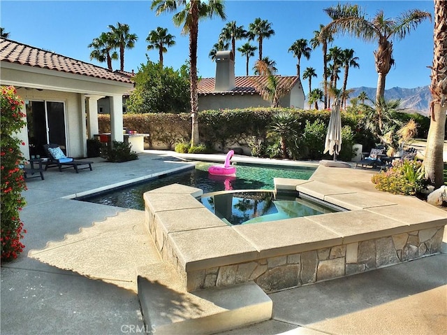 view of pool featuring an in ground hot tub, a mountain view, and a patio area