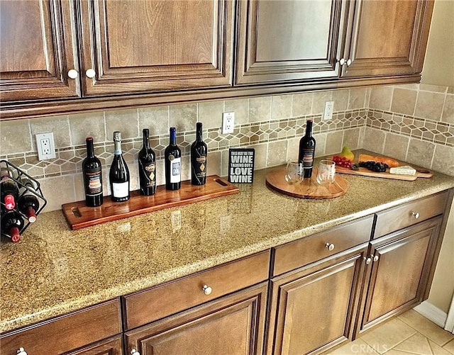 bar featuring light stone countertops, decorative backsplash, and light tile patterned flooring