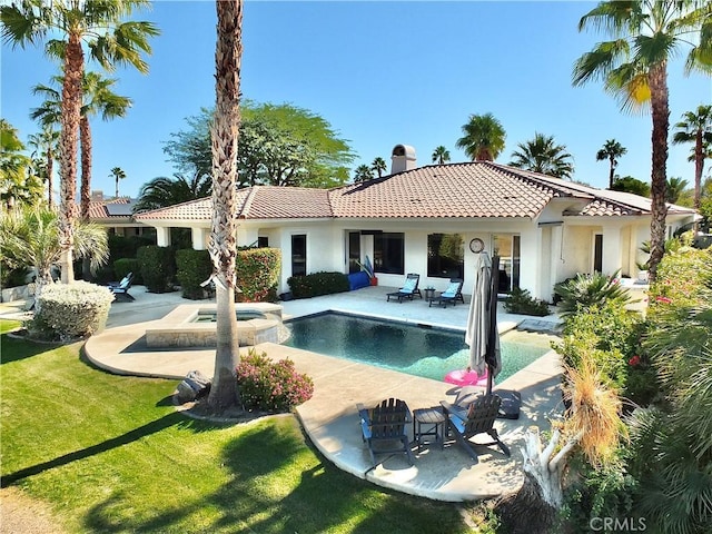 rear view of property featuring a pool with hot tub, a patio area, and a yard