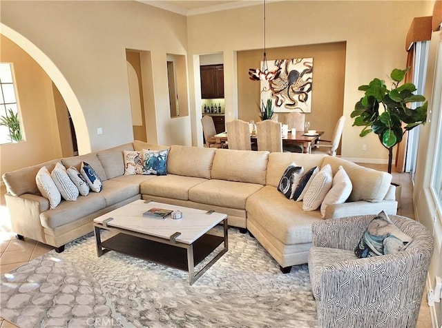 living room with light tile patterned flooring, an inviting chandelier, and ornamental molding