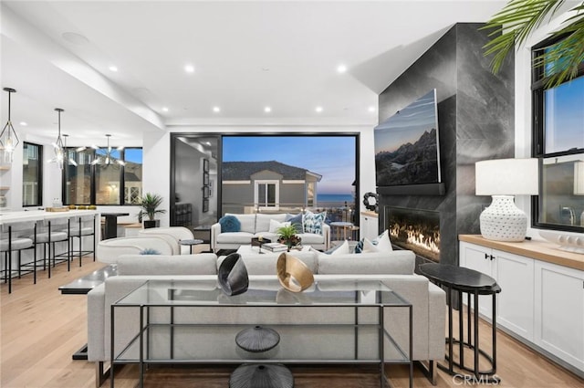 living area with light wood-style floors, recessed lighting, plenty of natural light, and a premium fireplace