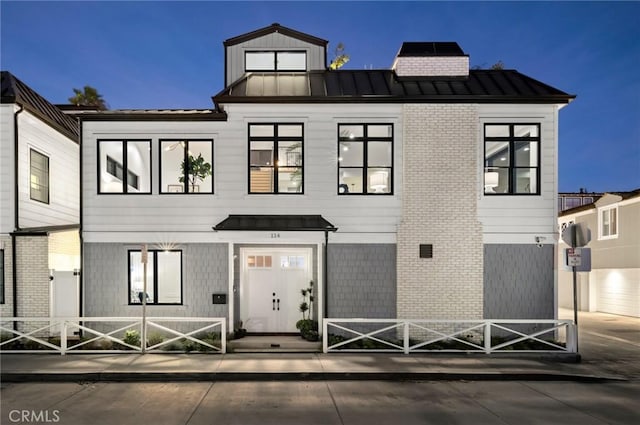 view of front facade featuring a standing seam roof, brick siding, and metal roof