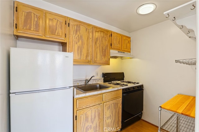 kitchen featuring gas stove, sink, light hardwood / wood-style floors, and white refrigerator