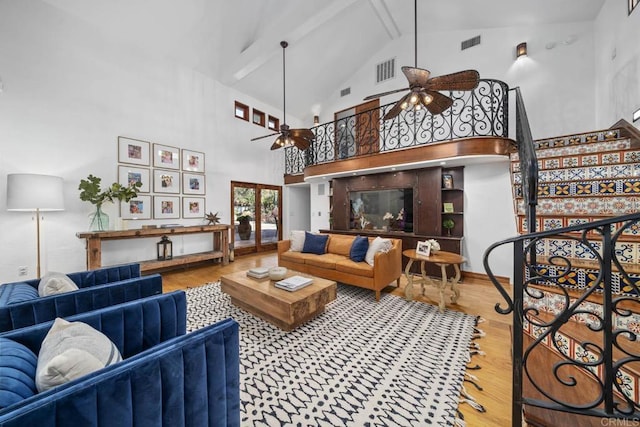 living room with hardwood / wood-style flooring, ceiling fan, beamed ceiling, and high vaulted ceiling