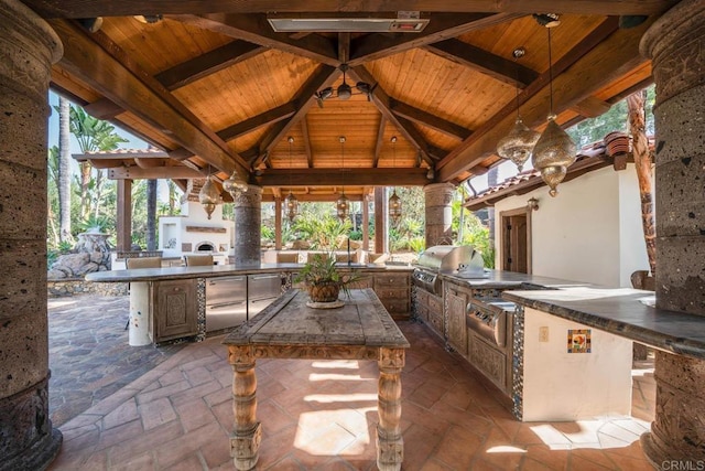 view of patio with a gazebo, grilling area, an outdoor fireplace, and exterior kitchen