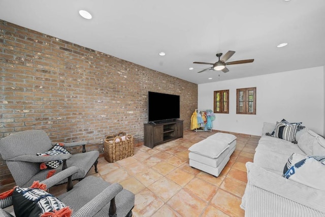 living room with ceiling fan, light tile patterned flooring, and brick wall