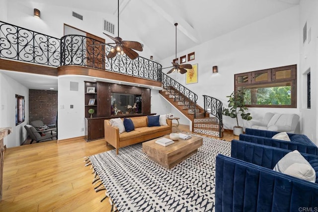 living room featuring ceiling fan, high vaulted ceiling, and light hardwood / wood-style flooring