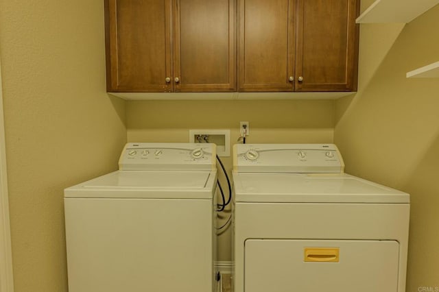 laundry room with washing machine and clothes dryer and cabinets