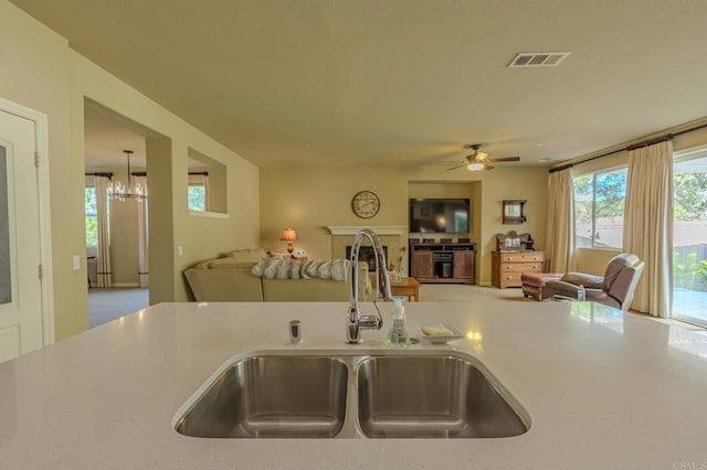 kitchen featuring ceiling fan with notable chandelier, sink, and decorative light fixtures