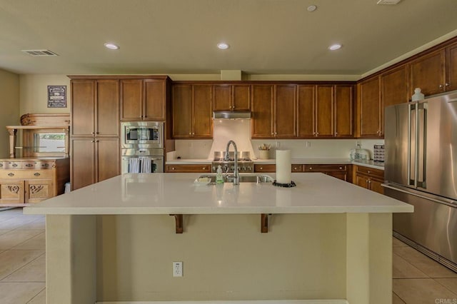 kitchen featuring a breakfast bar area, sink, a center island with sink, and appliances with stainless steel finishes