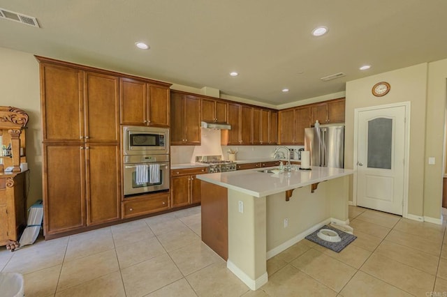 kitchen with sink, an island with sink, stainless steel appliances, and light tile patterned floors