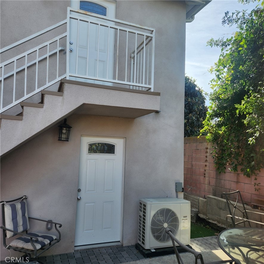 view of exterior entry with ac unit and a balcony