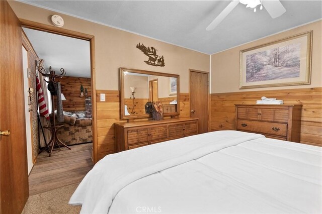 carpeted bedroom featuring ceiling fan and wooden walls