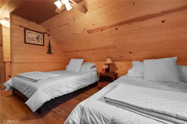 bedroom with ceiling fan, wood walls, wood-type flooring, and vaulted ceiling