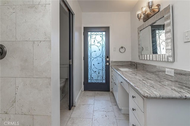 bathroom with a notable chandelier, vanity, and toilet