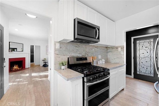 kitchen with white cabinetry, light wood-type flooring, and appliances with stainless steel finishes