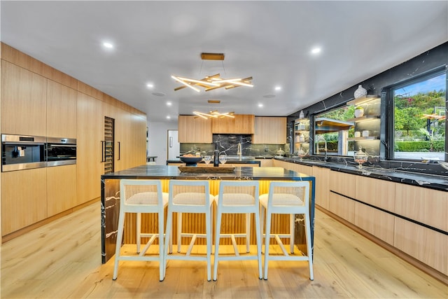 kitchen with light hardwood / wood-style floors, a breakfast bar area, and an island with sink