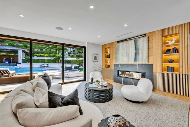 living room with hardwood / wood-style floors, built in features, wooden walls, and a tiled fireplace