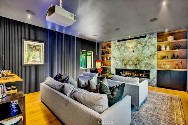 cinema room with a tile fireplace, hardwood / wood-style floors, and built in features