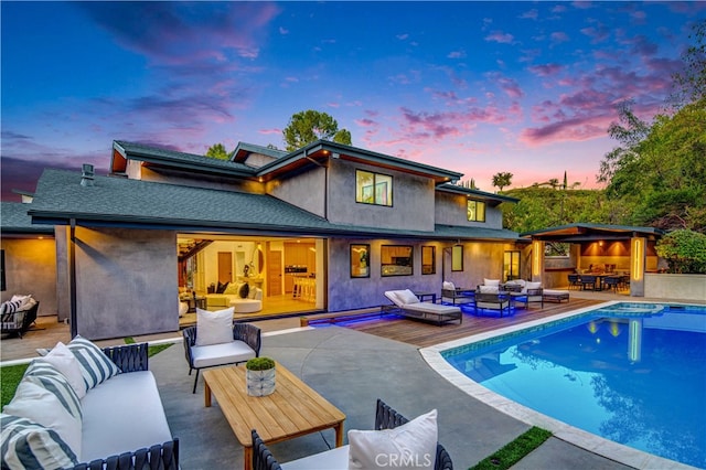 back house at dusk with outdoor lounge area and a patio area