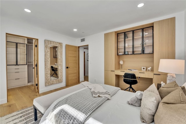 bedroom featuring built in desk and light wood-type flooring