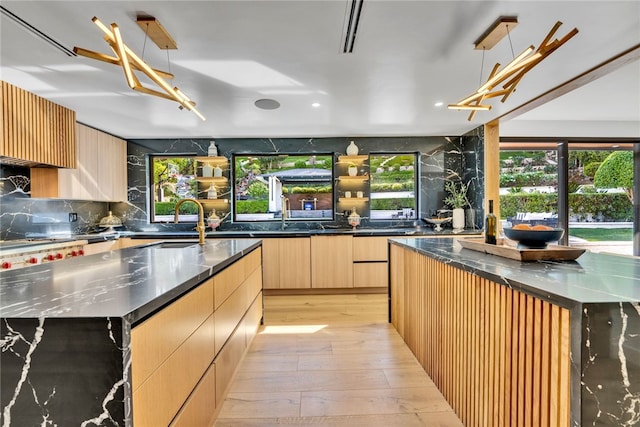 kitchen with sink, pendant lighting, a spacious island, and light hardwood / wood-style floors