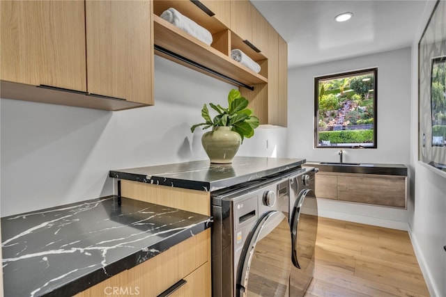 kitchen with washing machine and clothes dryer, light brown cabinets, and light hardwood / wood-style floors