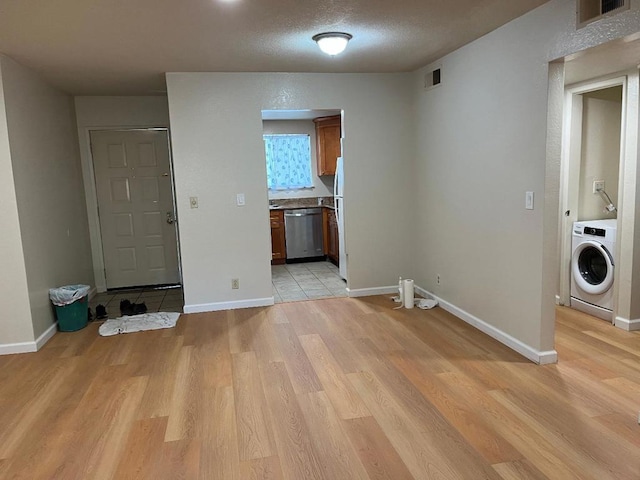 interior space with washer / clothes dryer, a textured ceiling, and light wood-type flooring