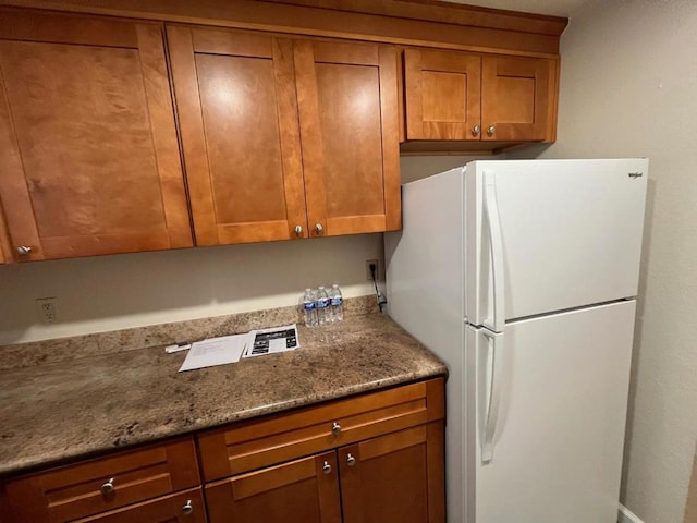 kitchen with white refrigerator and light stone countertops