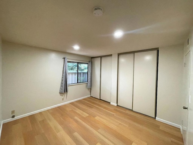 unfurnished bedroom with two closets and light hardwood / wood-style flooring