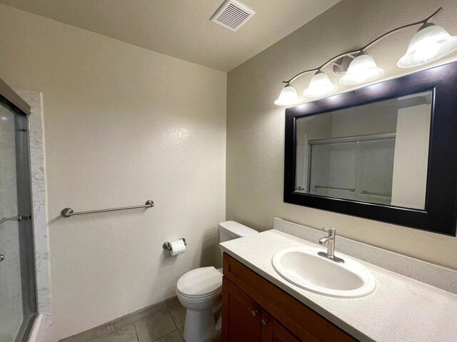 bathroom with tile patterned floors, toilet, a shower with door, and vanity