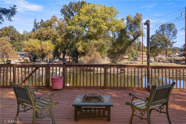 wooden terrace with a water view and an outdoor fire pit