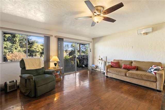 living room with a textured ceiling, ceiling fan, and dark hardwood / wood-style floors