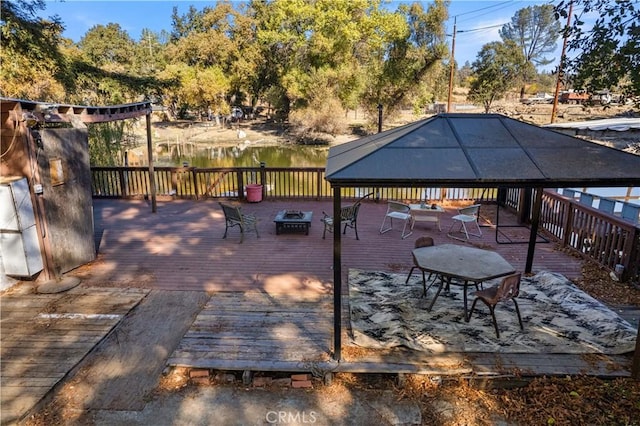 view of patio / terrace with a deck with water view and an outdoor fire pit