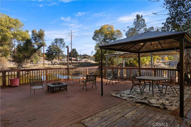 wooden deck with a gazebo, a water view, and an outdoor fire pit