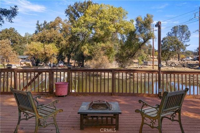 deck with a water view and a fire pit