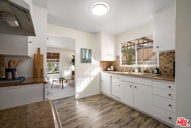 kitchen with backsplash, white cabinets, and sink