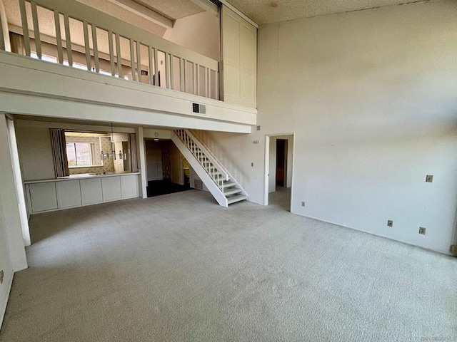 unfurnished living room with light carpet and a high ceiling