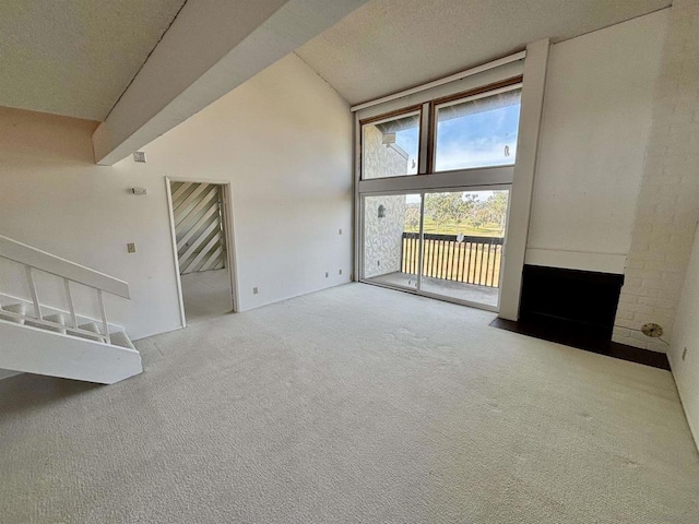 unfurnished living room with carpet floors, a textured ceiling, and high vaulted ceiling