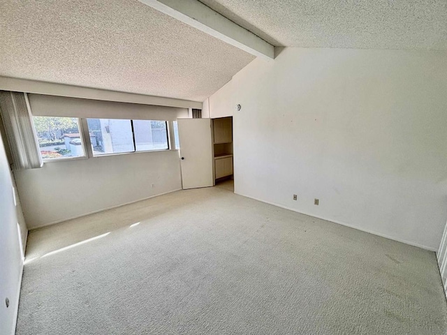 carpeted spare room featuring a textured ceiling and lofted ceiling with beams