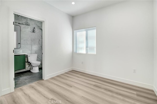 unfurnished bedroom featuring connected bathroom and light hardwood / wood-style flooring