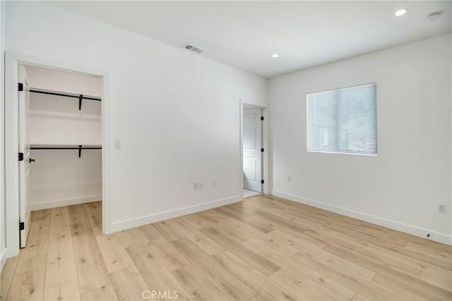 unfurnished bedroom featuring a closet, light hardwood / wood-style flooring, and a walk in closet