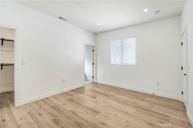 unfurnished bedroom featuring a spacious closet and light wood-type flooring