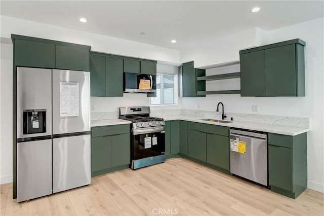 kitchen featuring sink, green cabinets, stainless steel appliances, and light wood-type flooring