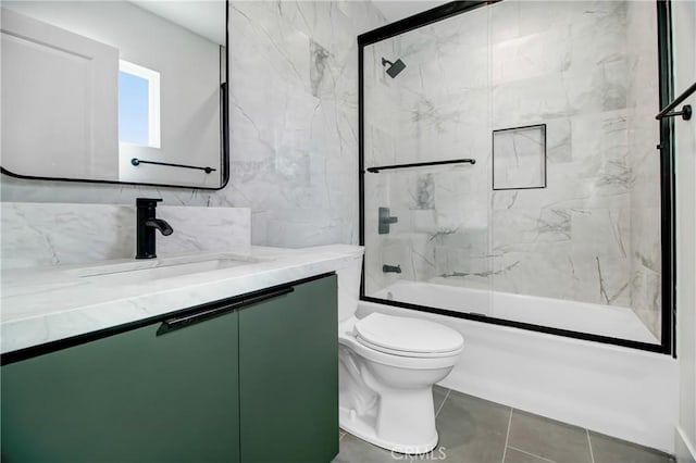 full bathroom featuring toilet, vanity, tile walls, tile patterned flooring, and shower / bath combination with glass door