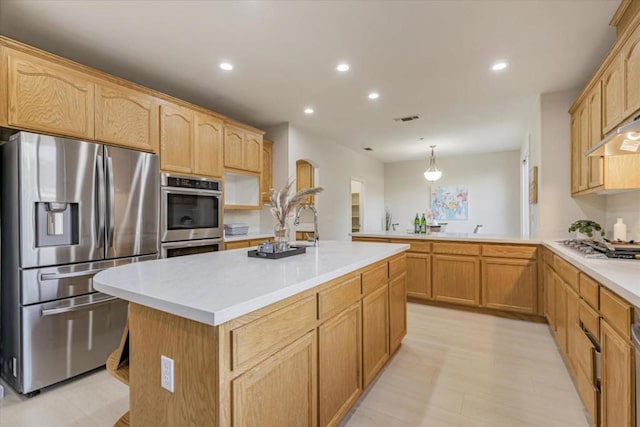 kitchen featuring pendant lighting, an island with sink, kitchen peninsula, stainless steel appliances, and extractor fan