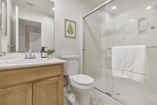 bathroom with a shower with door, vanity, and toilet